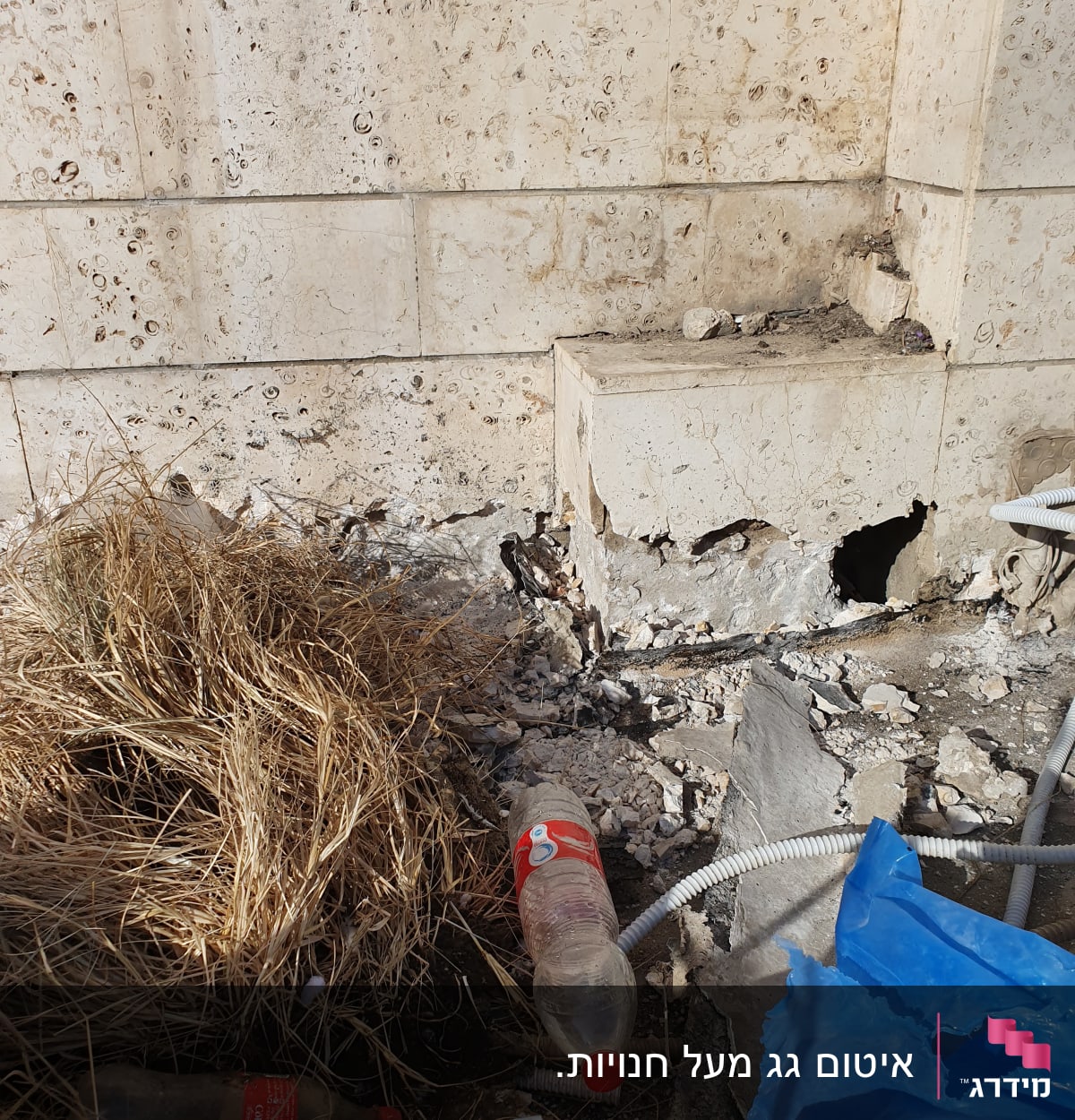 קיר אבן עם חורים וסדקים, צינור גמיש על הקרקע
